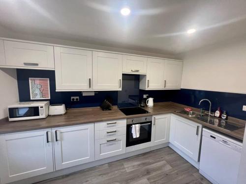 a kitchen with white cabinets and white appliances at 16 Macgregor court, Oban in Oban