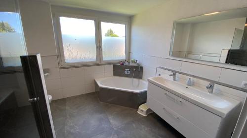 a bathroom with a tub and a sink and a mirror at Villa Herzland Allgäu mit großem Garten und gemütlichem Kaminfeuer inklusive KÖNIGSCARD, Skipass, Bergbahn, Therme inkl in Lechbruck