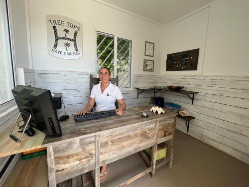 a woman sitting at a desk with a computer at Treetops Hotel in Caye Caulker