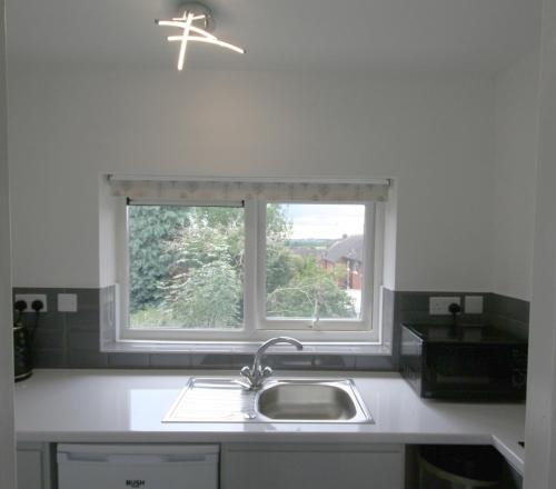 cocina con fregadero y ventana en Sheffield serviced apartment, en Greenhill