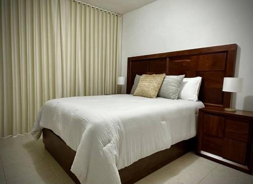 1 dormitorio con 1 cama grande con sábanas y almohadas blancas en Departamento Longoria 4A, en Matamoros