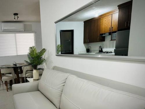 a living room with a white couch and a kitchen at Departamento Longoria 4A in Matamoros
