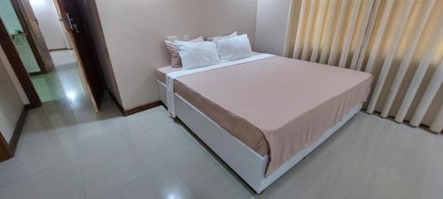 une petite chambre avec un lit avec des draps blancs et des oreillers dans l'établissement Sami BnB - Apt 05 Makongo after Mlimani City, à Dar es Salaam