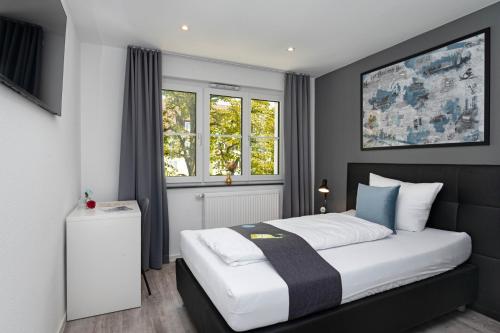 a bedroom with a bed and two windows at Hotel Das Q Spaichingen in Spaichingen
