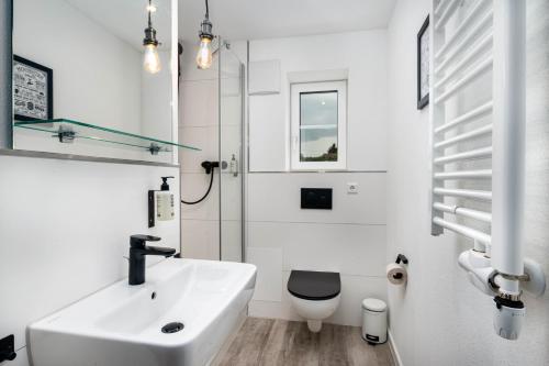 uma casa de banho branca com um lavatório e um WC em Hotel Das Q Spaichingen em Spaichingen
