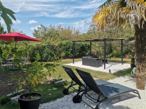 a chair and an umbrella next to a swing at Love Room avec spa in Nérac