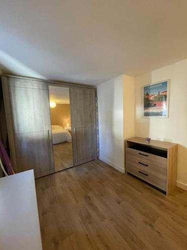 Zimmer mit einem Schlafzimmer mit einer Kommode und einem Spiegel in der Unterkunft Maison Hyper Centre Brive in Brive-la-Gaillarde