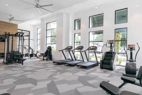 a gym with treadmills and ellipticals in a room with windows at West Midtown Jewel in Atlanta