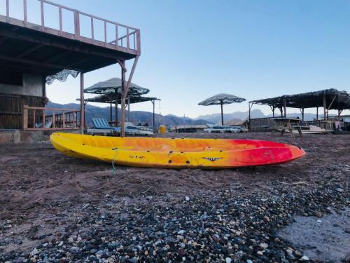 a yellow and red kayak on a beach with umbrellas at فللبررر in Nuweiba