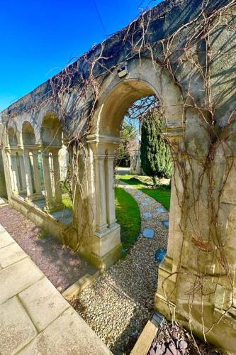 an old stone building with an arch in a yard at Cosy Stylish Studio Apartment in Trowbridge
