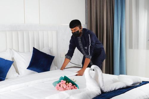 a man making a bed in a hotel room at شقق زوايا الماسية العوالي in Al Madinah