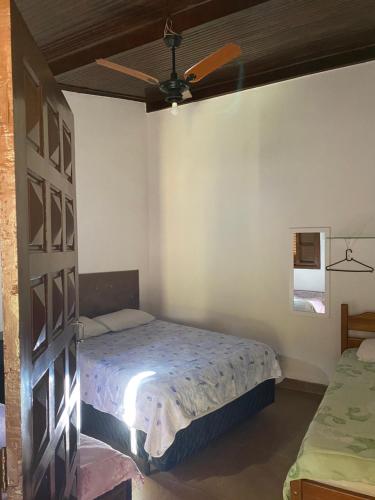 een slaapkamer met een bed en een plafondventilator bij Recanto Primavera in Boicucanga
