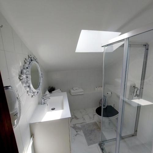 a white bathroom with a sink and a shower at Soleil Bleu in Vila Nova de Milfontes