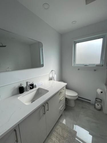 a white bathroom with a sink and a toilet at Beautiful Renovated House Laval in Laval