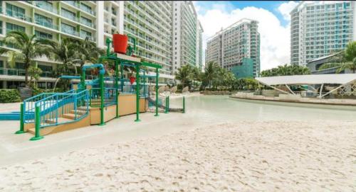 a playground in the middle of a beach with tall buildings at 1 Bedroom Unit with Massage Chair, Karaoke, Smart TV at Azure Urban Resort in Manila