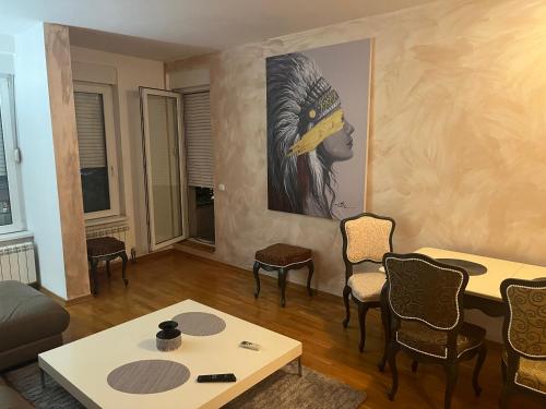 a living room with a table and chairs and a painting at THE FIVE-Voždovac Apartment in Dušanovac (historical)
