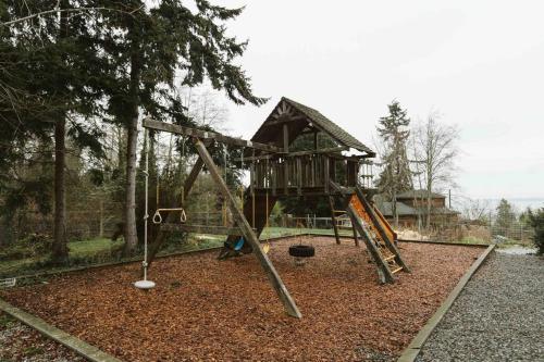a playground with a tree house and a swing at Stunning Home, Sound View, Sauna and Covered Deck in Vashon