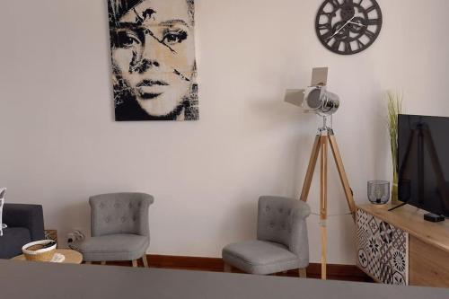 una sala de estar con 2 sillas y una foto en la pared en L'Escapade Appartement T1 douillet tout confort en Roanne