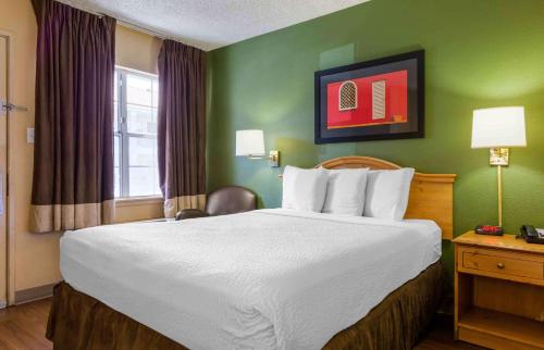 a large bed in a hotel room with green walls at Extended Stay America Suites - Phoenix - Scottsdale - Old Town in Scottsdale