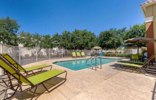 a swimming pool with lawn chairs and an umbrella at Extended Stay America Suites - Phoenix - Scottsdale - Old Town in Scottsdale