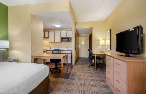 a hotel room with a bed and a desk with a television at Extended Stay America Select Suites - Dallas - Las Colinas - Meadow Creek Dr in Irving