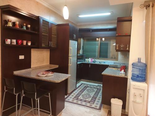 Elegant Home في عمّان: مطبخ مع خزائن خشب داكنة وقمة كونتر