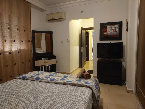 Elegant Home في عمّان: غرفة نوم بسرير وتلفزيون بشاشة مسطحة