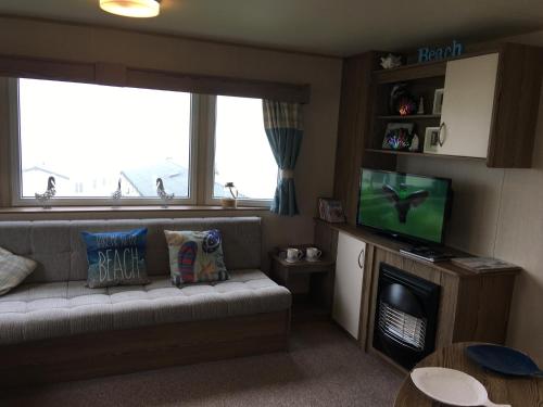 a living room with a couch and a television at Devon Cliffs Exmouth Sandy Bay 3 bedrooms in Exmouth