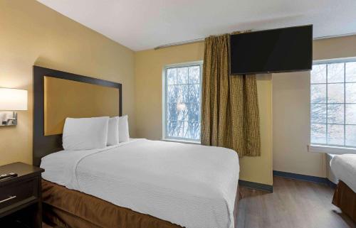 a hotel room with a large bed and two windows at Extended Stay America Select Suites - St Louis - Airport - Central in Bridgeton