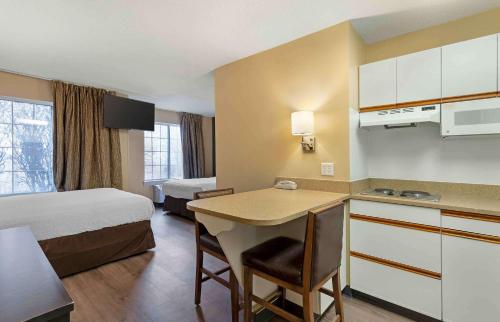 a hotel room with a bed and a kitchen with a desk at Extended Stay America Select Suites - St Louis - Airport - Central in Bridgeton