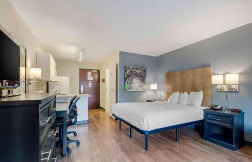 a hotel room with a bed and a desk and a kitchen at Extended Stay America Suites - Dallas - Coit Road in Dallas