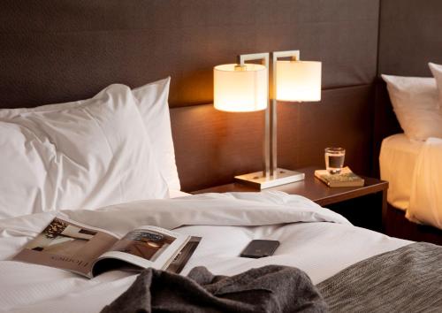 a bedroom with a bed with a book and a lamp at Rydges Wellington in Wellington