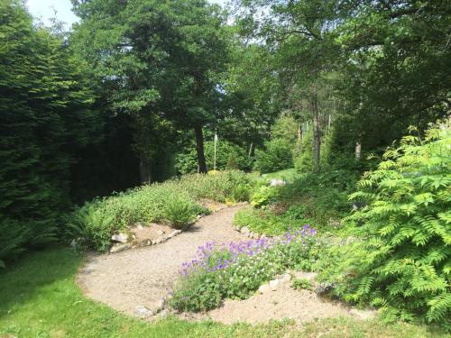 a path in a garden with flowers and trees at Le Manoir Au Lac in Gérardmer
