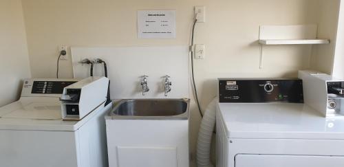 a small kitchen with a sink and a microwave at Commodore Motor Lodge in Ashburton