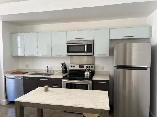 a kitchen with white cabinets and a stainless steel refrigerator at Historic Downtown LA Loft - Urban Charm in Los Angeles