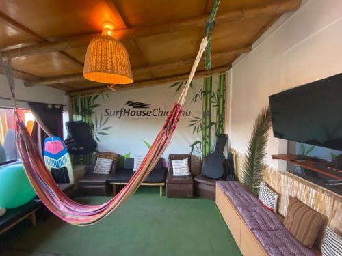 een kamer met een hangmat en een flatscreen-tv bij Surf House Chicama in Puerto Chicama