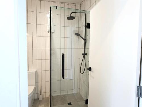 a shower with a glass door in a bathroom at U Suites on Trieste Way in Paraparaumu