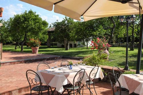 a table with white tables and chairs under an umbrella at Agriturismo Galea in Riposto