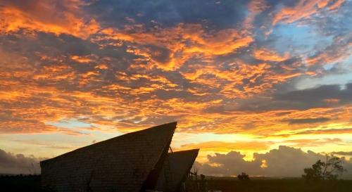 un coucher de soleil sur un bâtiment avec un ciel nuageux dans l'établissement Hars Garden Sumba, à Waingapu