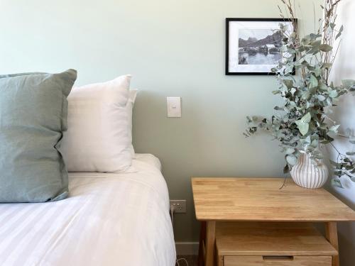a bedroom with a bed and a table with a vase on it at Little Island Apartments in Hobart