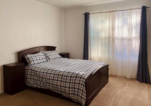 a bedroom with a bed with a plaid blanket and a window at Spacious Fully-Equipped Home in Algonquin