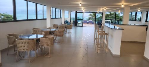 um restaurante com mesas e cadeiras e um bar em Flat La Ursa da Praia em Porto de Galinhas