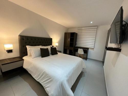 a bedroom with a large white bed with black pillows at Hotel Zuriel Boutique in Cartagena de Indias