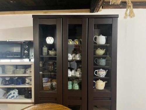 a wooden cabinet filled with cups and dishes at ゲストハウス餓鬼大将 in Omachi