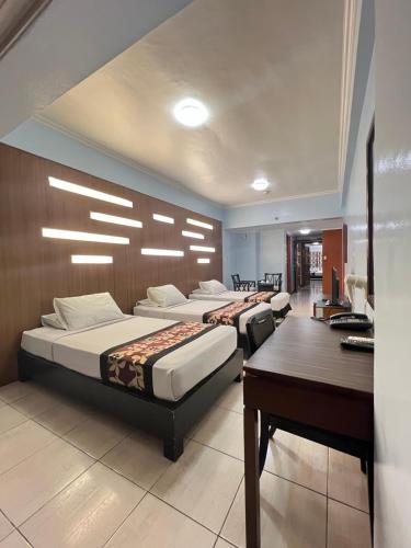 ein Hotelzimmer mit drei Betten und einem Schreibtisch in der Unterkunft Jupiter Suites in Manila