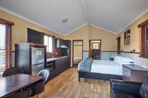 a bedroom with a bed and a kitchen and a table at NRMA South West Rocks Holiday Park in South West Rocks
