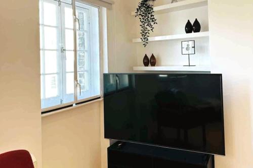 einen Flachbild-TV im Wohnzimmer mit 2 Fenstern in der Unterkunft 2Bed Apartment Farringdon St Paul Long Stay Discounts By Cozystays in London
