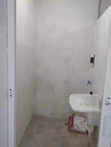 a white bathroom with a sink and a toilet at Casa laranja cabuçu in Saubara
