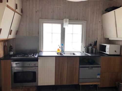 a kitchen with a sink and a stove and a window at Houses by the sea near the city in Lidingö