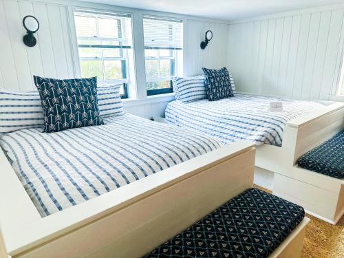 two beds sitting in a room with windows at The Centerboard Nantucket in Nantucket